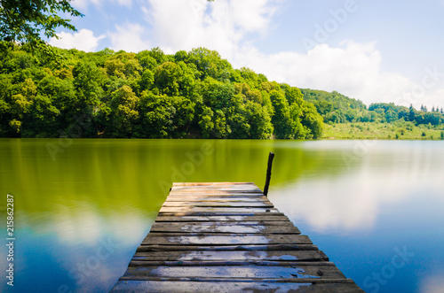 Wooden pier or jetty and a boat on lake sunset and sky reflection water.