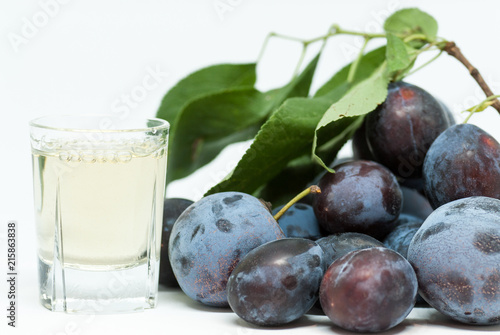 romanian plum brandy known as tuica or tzuica and heap of ripe plums on white