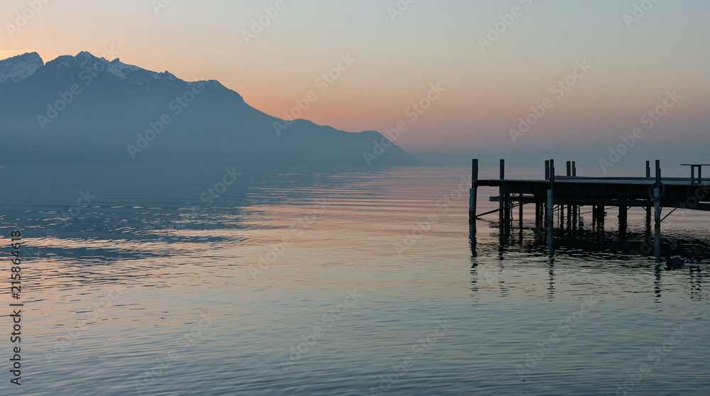 Panoramic view at old wooden jetty and alps on the shores of lake Geneva during sunset in Montreux, Switzerland