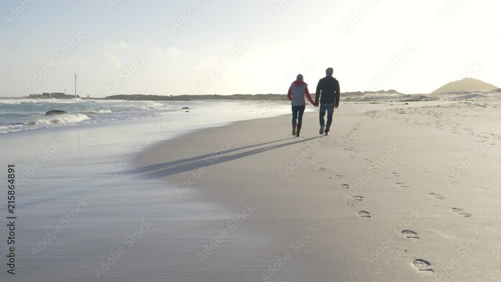 Couple walking on deserted beach on winter afternoon Couple walking on deserted beach on winter afternoon