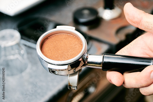 Close-up shot of barista espresso machine portafilter, filled with coffee