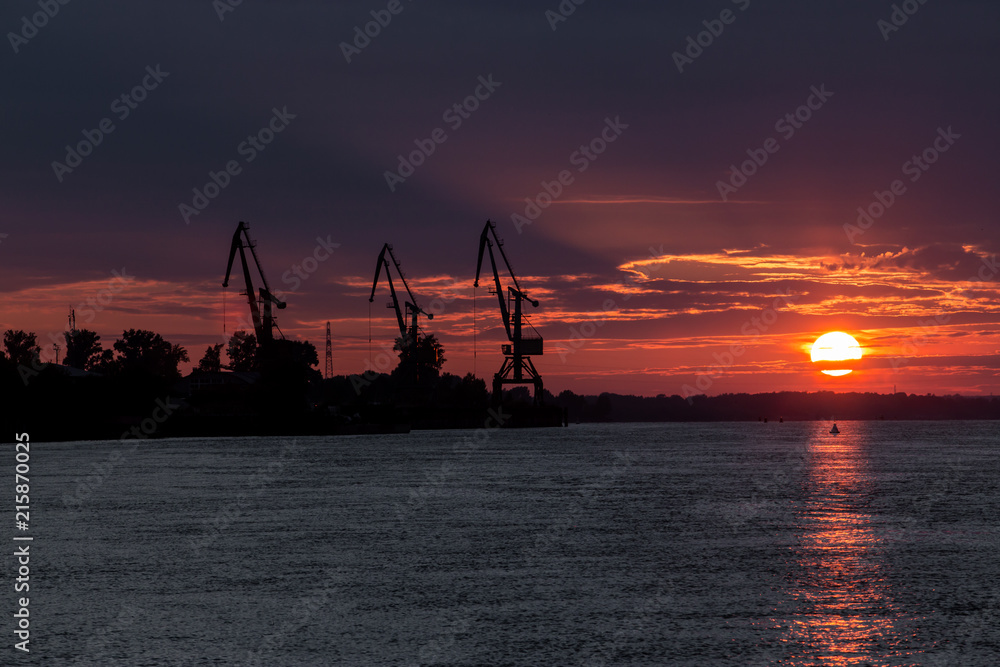 Port cranes and a bloody sunset over the river
