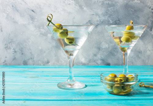 Martini cocktail with green olives on blue wood background