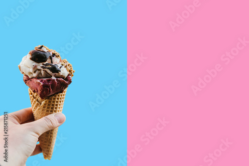 A female hand holds ice cream on a colored background. Nearby place for text.