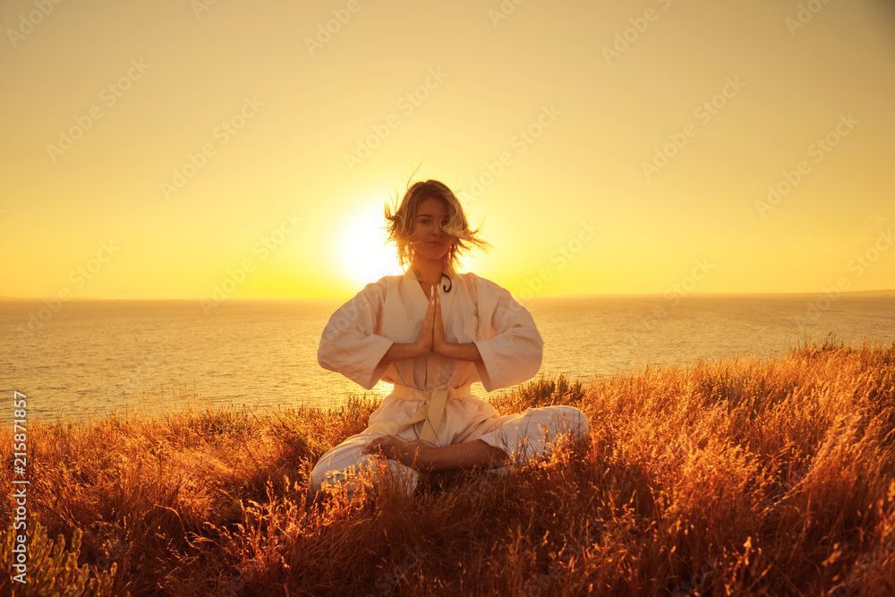 Silhouette of a girl in a kimono on the beach, Sitting in a Lotus position on the background of sunrise. The concept of meditation.