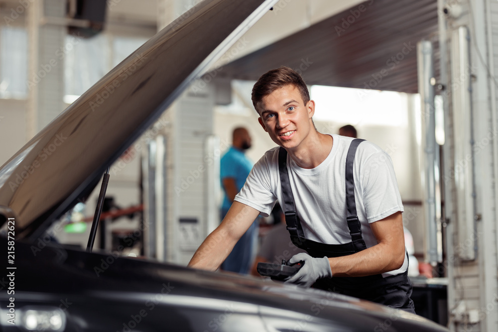 A young mechanic is checking indicators and the results of his work A young mechanic is checking indicators and the results of his work