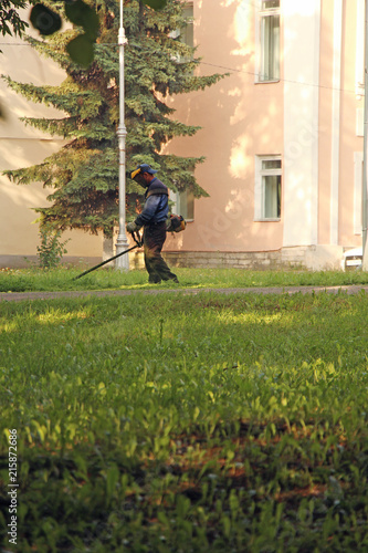 lawnmower, mows the grass on the lawn with a trimmer