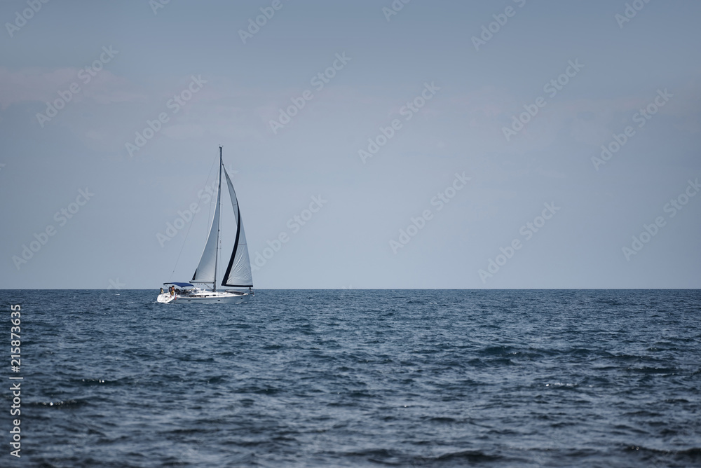 White yacht with sails in the open sea.
