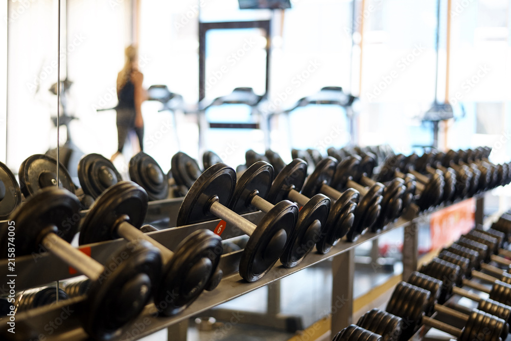Naklejka premium Dumbbells on the rack in the sports hall of the club.