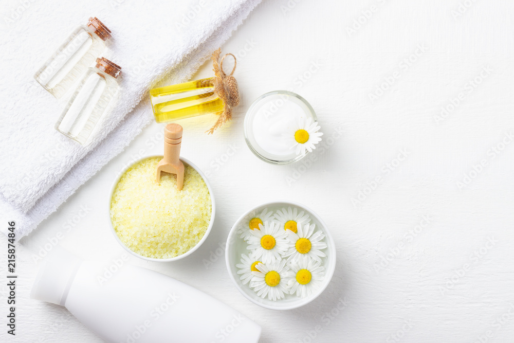Spa background with bath yellow sea salt, natural cream and chamomile on white wooden table Spa background with bath yellow sea salt, natural cream and chamomile on white wooden table