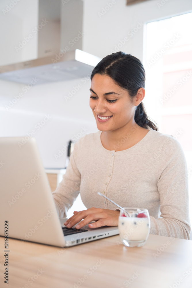 Woman sitting at a table looking at a laptop pc Woman sitting at a table looking at a laptop pc