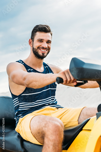 happy young man on all-terrain vehicle looking at camera in front of cloudy sky © LIGHTFIELD STUDIOS