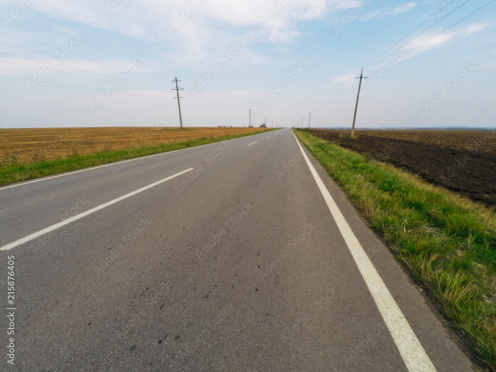 View of the highway in the countryside and fields under the blue sky View of the highway in the countryside and fields under the blue sky