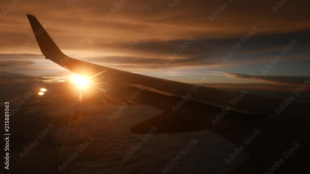View of airplane with silhouette wing flying in the sky over sunset cloud with the beautiful golden sun. View of airplane with silhouette wing flying in the sky over sunset cloud with the beautiful golden sun.