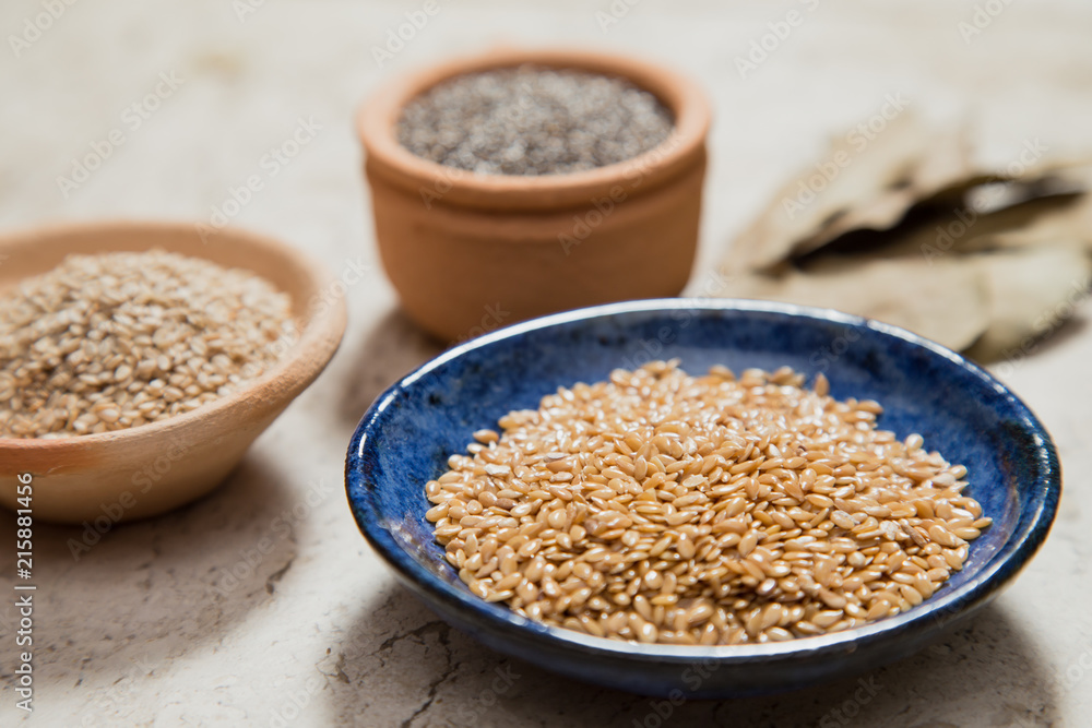 Composition with pottery bowls containing chia seeds, linum seeds, and sesame. Laurel Nobilis leafs. Marble surface. Composition with pottery bowls containing chia seeds, linum seeds, and sesame. Laurel Nobilis leafs. Marble surface.
