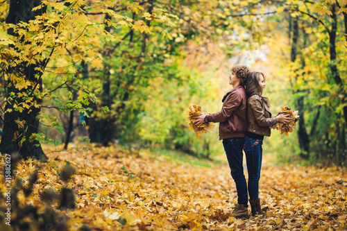 Loving happy couple in autumn in park holding autumn maple leaves in hands. © Marina Varnava