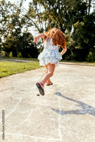 Portrait of a redhead little girl playing hopscotch photo