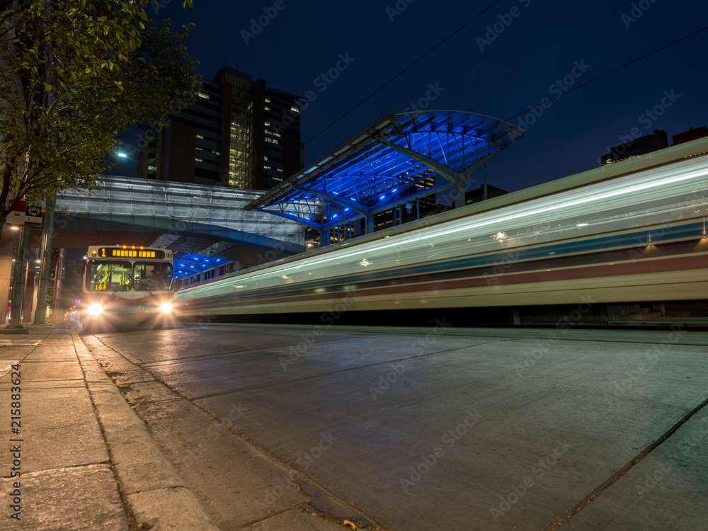 A transit bus is passed by a train at a station at night. Stock Photo ...