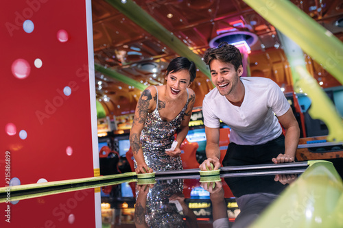 Canvas Print Man and woman playing air hockey game at a gaming parlour