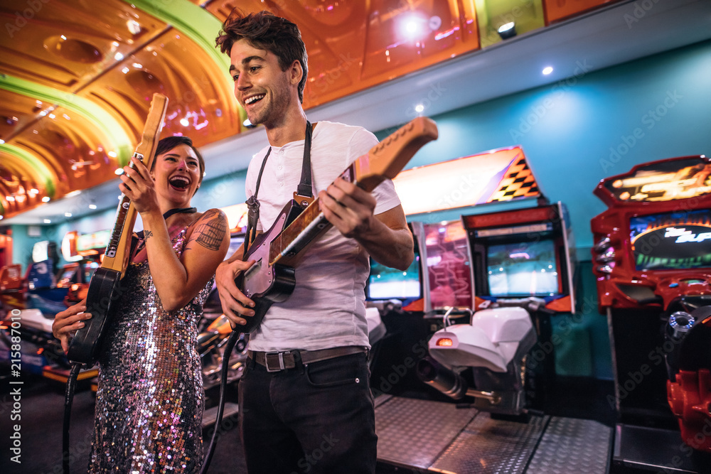 Excited couple holding gaming guitars in hand having fun