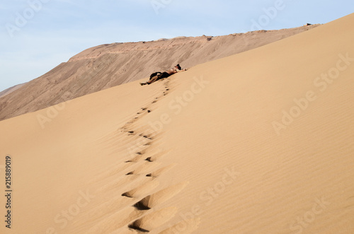 Guy resting after climb to the enormous sand dune photo