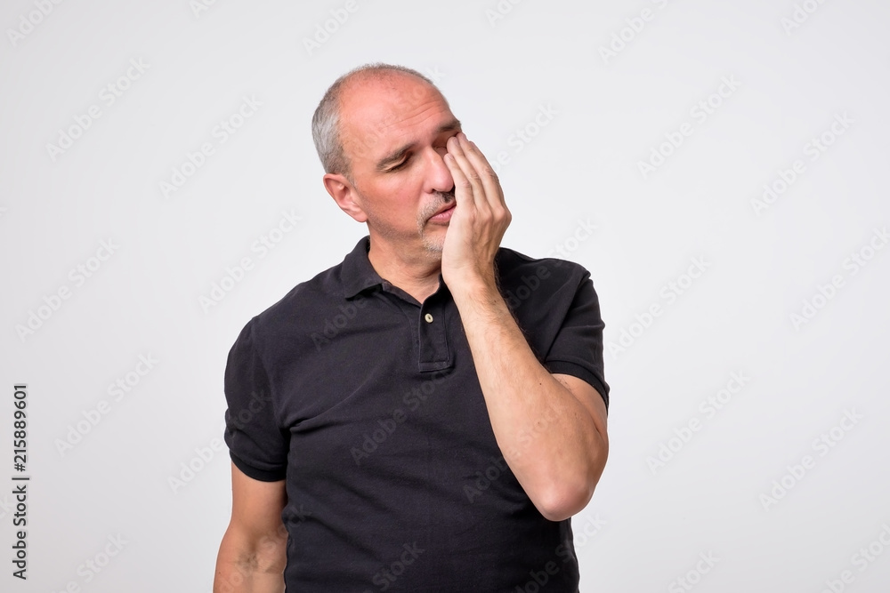 Closeup portrait of mature man wearing black shirt with tooth ache isolated on gray background. Concept of dental problems and healthcare Closeup portrait of mature man wearing black shirt with tooth ache isolated on gray background. Concept of dental problems and healthcare
