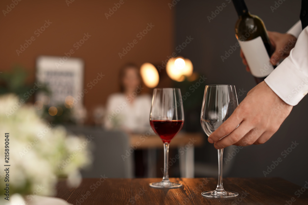 Man pouring wine into glass in restaurant
