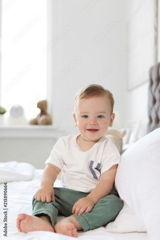 Adorable little baby sitting on bed at home Adorable little baby sitting on bed at home