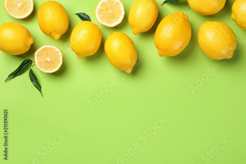 Flat lay composition with whole and sliced lemons on color background