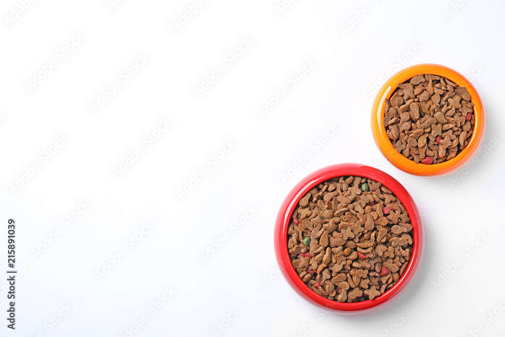 Bowls of dry pet food on white background, top view Bowls of dry pet food on white background, top view