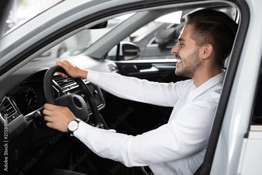 Young man testing new car in salon Young man testing new car in salon