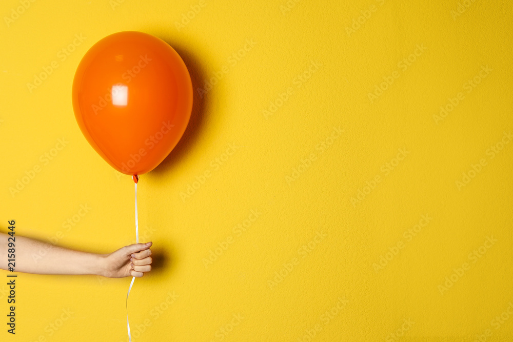 Woman holding orange balloon on color background - obrazy, fototapety, plakaty 