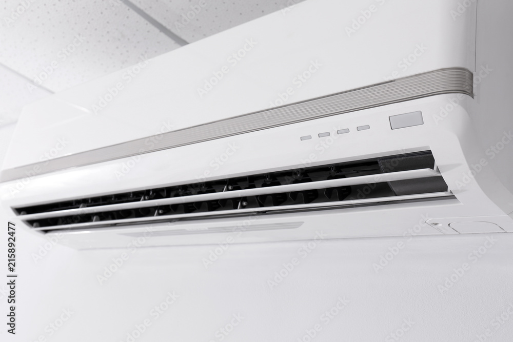 Modern air conditioner on white wall indoors, closeup view Modern air conditioner on white wall indoors, closeup view