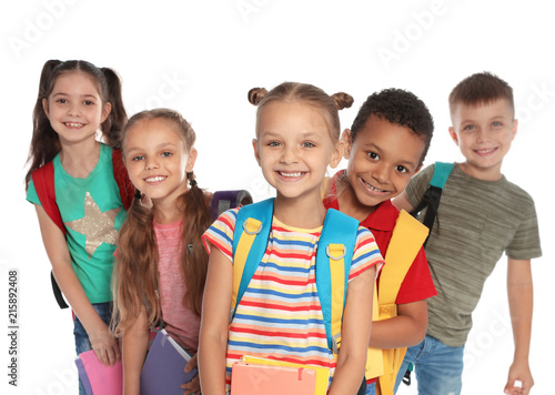 Group of little children with backpacks and school supplies on white background