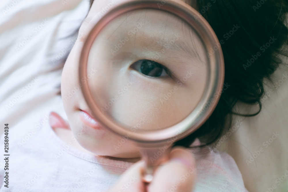 little girl playing with a magnifying glass