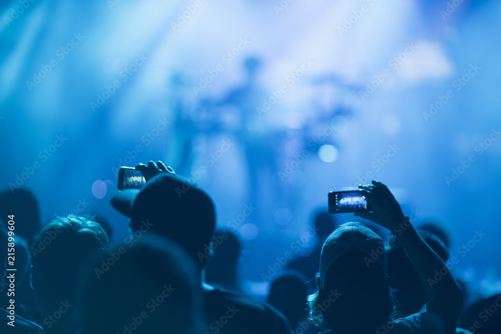 © Robert Kohlhuber/Stocksy - Sillhouettes of concert crowd in front of bright stage lights