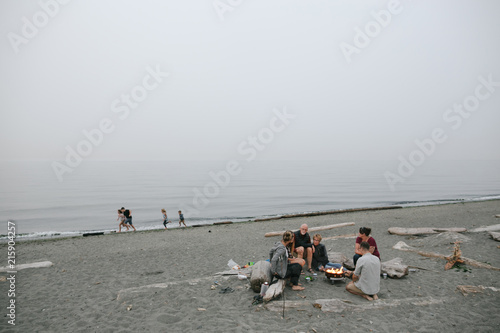 Multi generational family hanging out together around fire on the beach photo