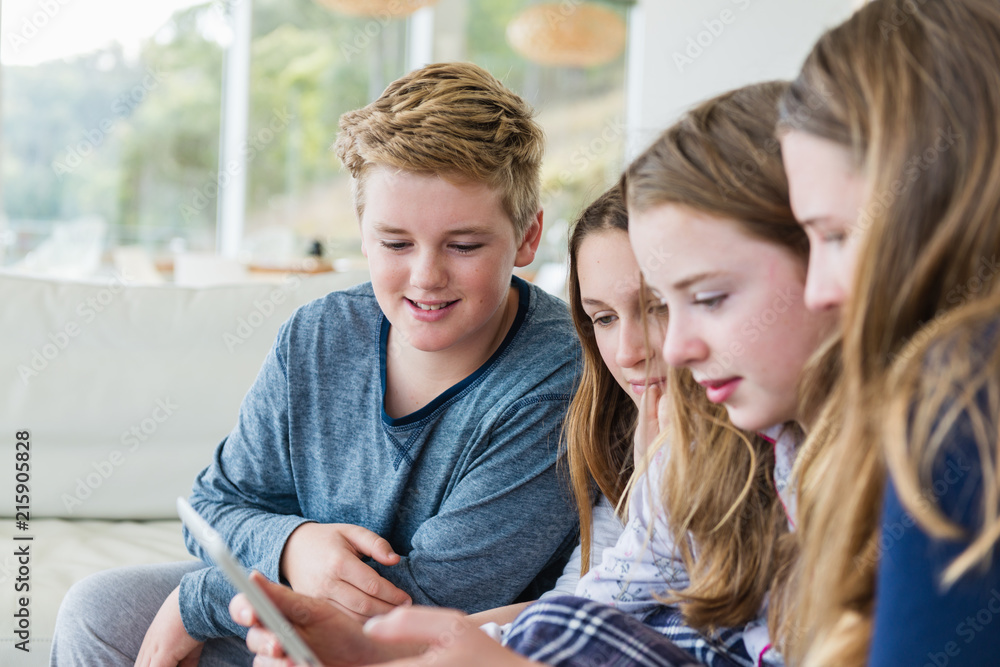 group of young teens watching something on an ipad group of young teens watching something on an ipad