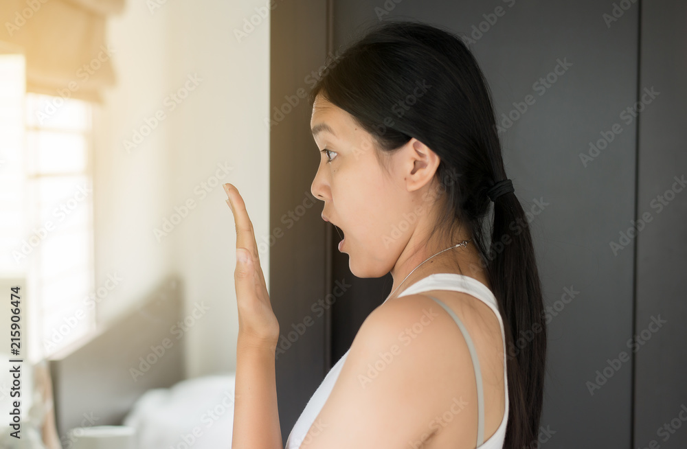 Asian woman covering her mouth and smell her breath with hands upter wake up,Bad smell,Selective focus Asian woman covering her mouth and smell her breath with hands upter wake up,Bad smell,Selective focus