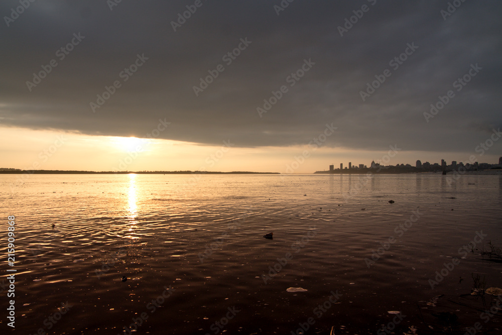 Naklejka premium water pollution in a river with a city view on the horizon during the sunset