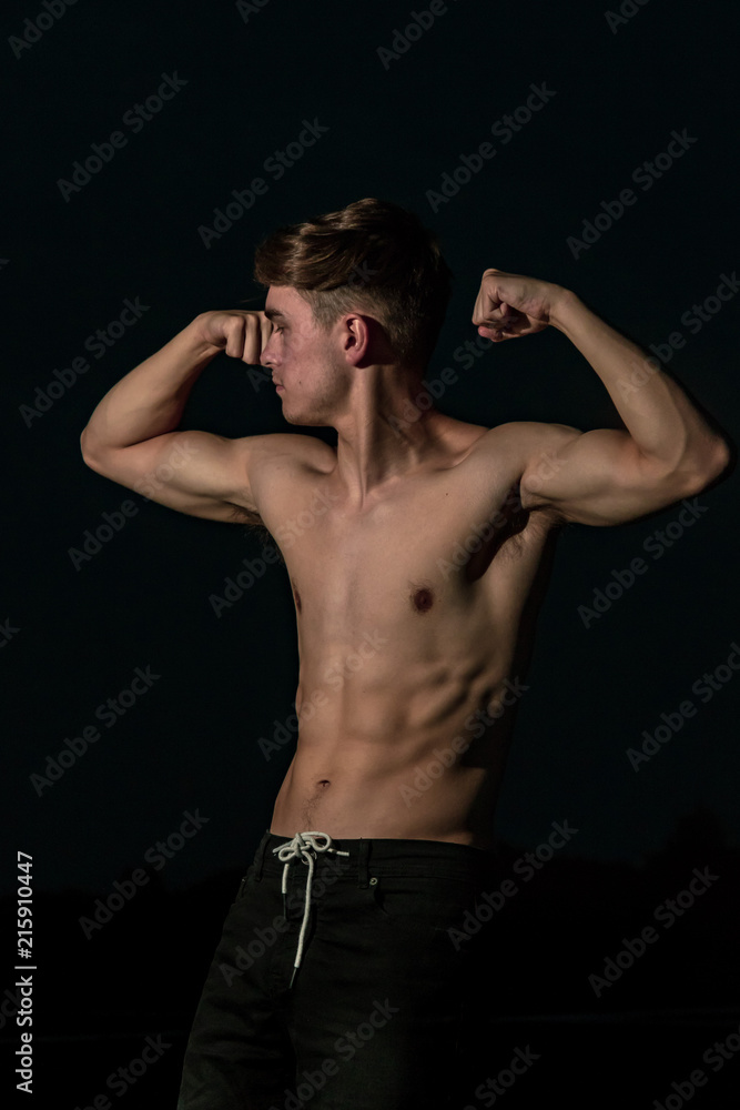 Young adult male posing shirtless at sunset