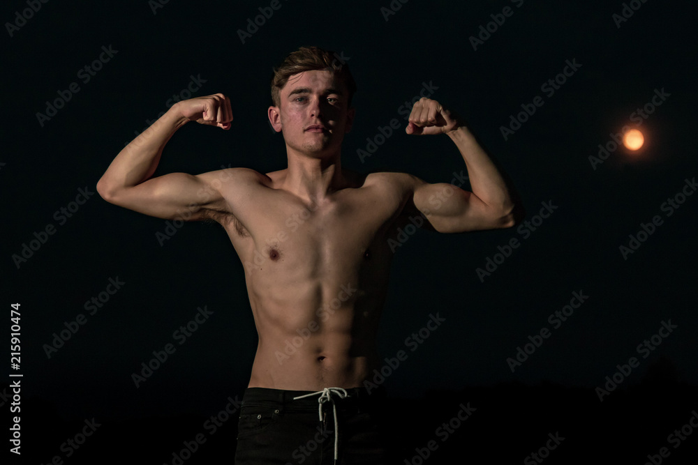 Young adult male posing shirtless at sunset