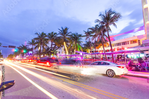 Ocean Drive scene at sunset with lights, palm trees, cars and people having fun, Miami beach. Art Deco style hotels and restaurants at sunset on Ocean Drive, world famous destination for its nightlife