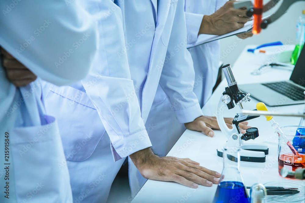 Fototapeta premium The research team is analyzing the results of biochemical experiments by using microscope, chemical in beaker and save the data in the laptop at laboratory room.