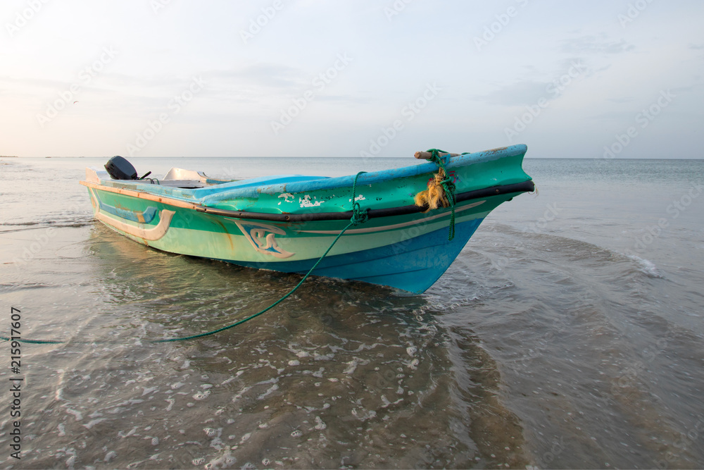 Small fishing boat in early sunset light on Nilaveli beach in Trincomalee Sri Lanka Asia