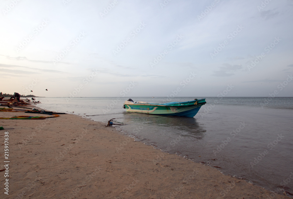 Fototapeta premium Small fishing boat on shore at sunset on Nilaveli beach in Trincomalee Sri Lanka Asia