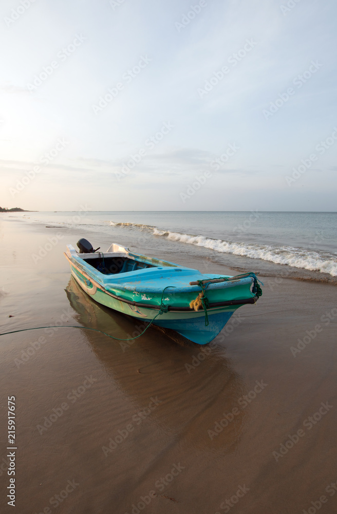 Sunset view of small fishing boat on Nilaveli beach in Trincomalee Sri Lanka Asia Sunset view of small fishing boat on Nilaveli beach in Trincomalee Sri Lanka Asia