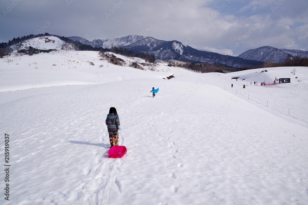 雪山でソリ遊びをする子供 雪山でソリ遊びをする子供