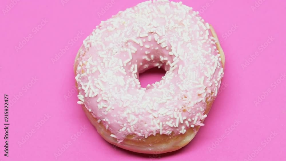 Spinning donut on pink table, high-sugar dessert causes diabetes, temptation Spinning donut on pink table, high-sugar dessert causes diabetes, temptation