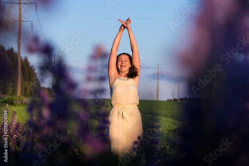 Nice woman in a green field and purple lupines